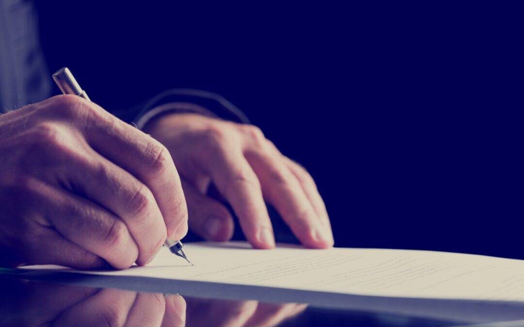 A close-up image of an adult male's hands as he writes on a piece of paper